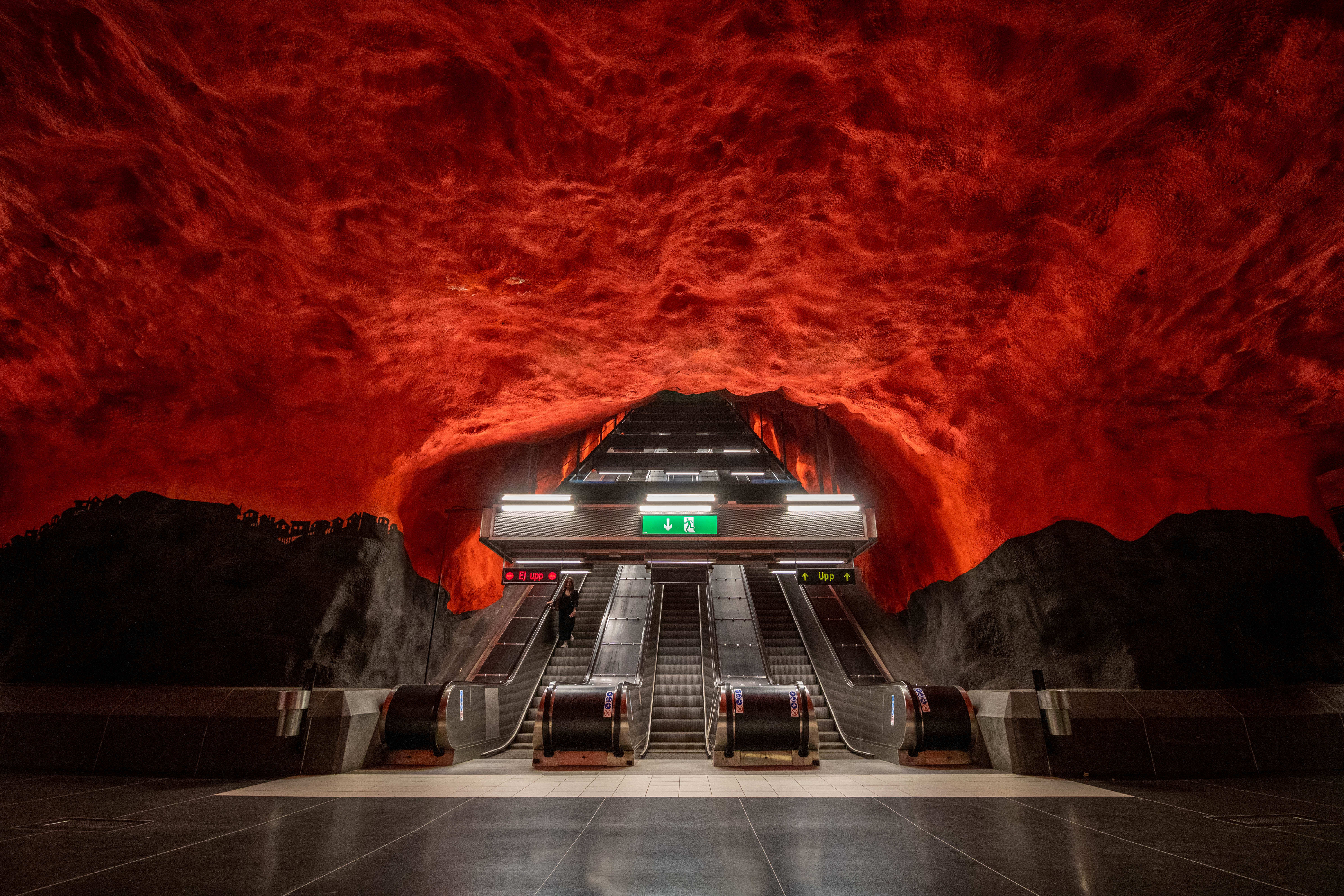 Photo of a an underground subway with a sea of red engulfing a set of escalators.