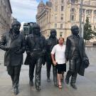 Gonzales stands among four metal statues of The Beatles on a London street.