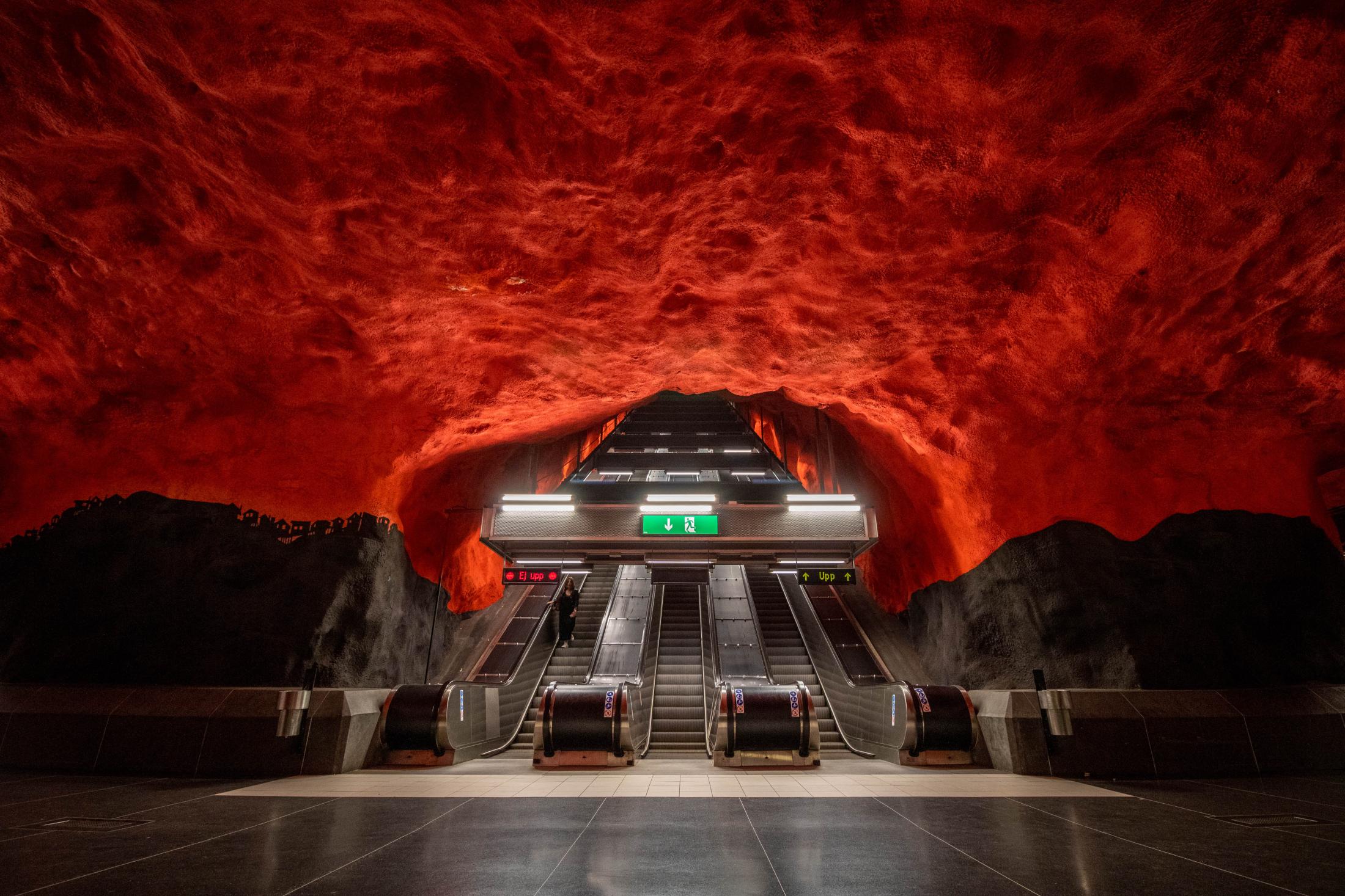 Photo of a an underground subway with a sea of red engulfing a set of escalators.