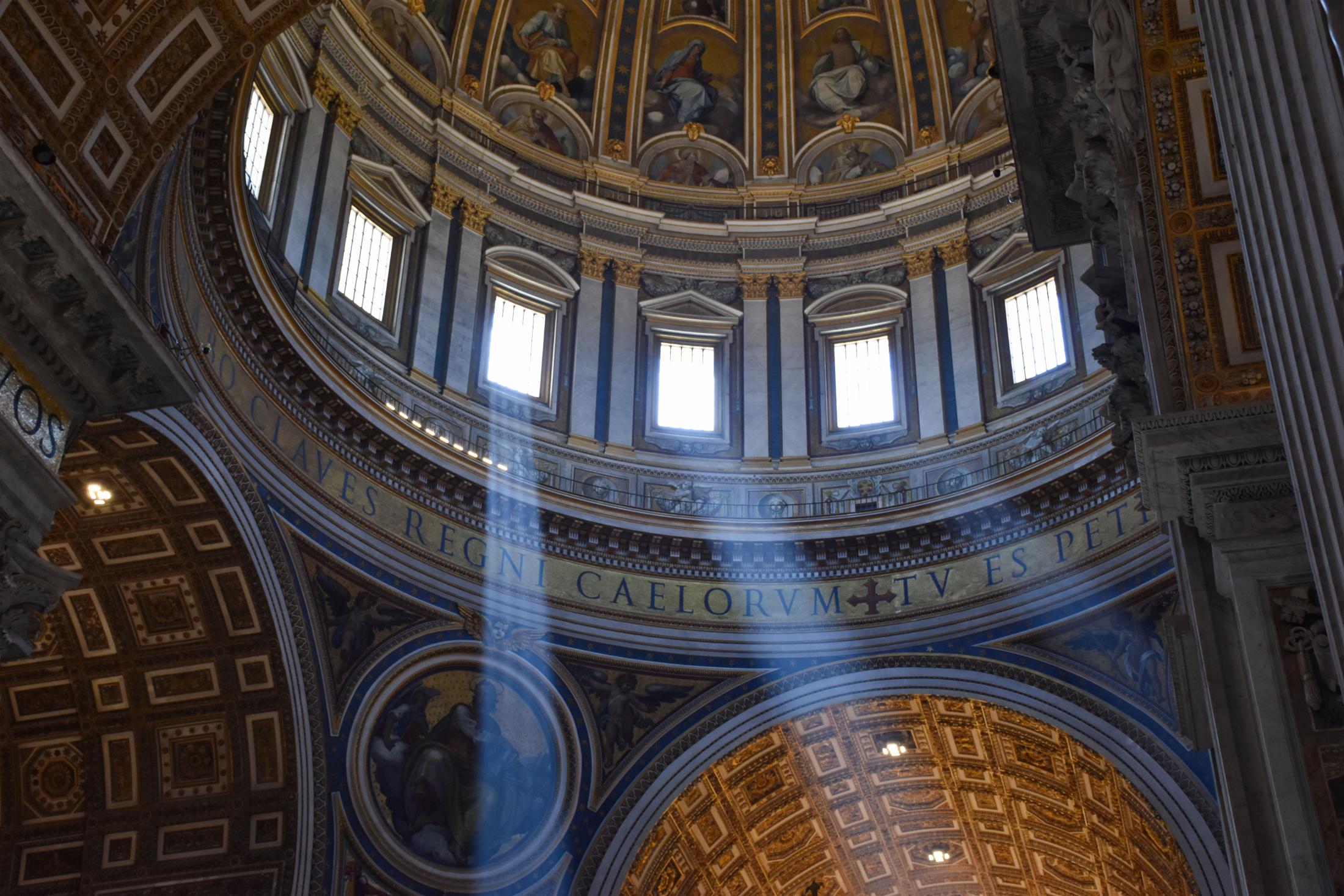Photo of the inside of Saint Peter’s Basilica, showing beams of light glistening through the windows.