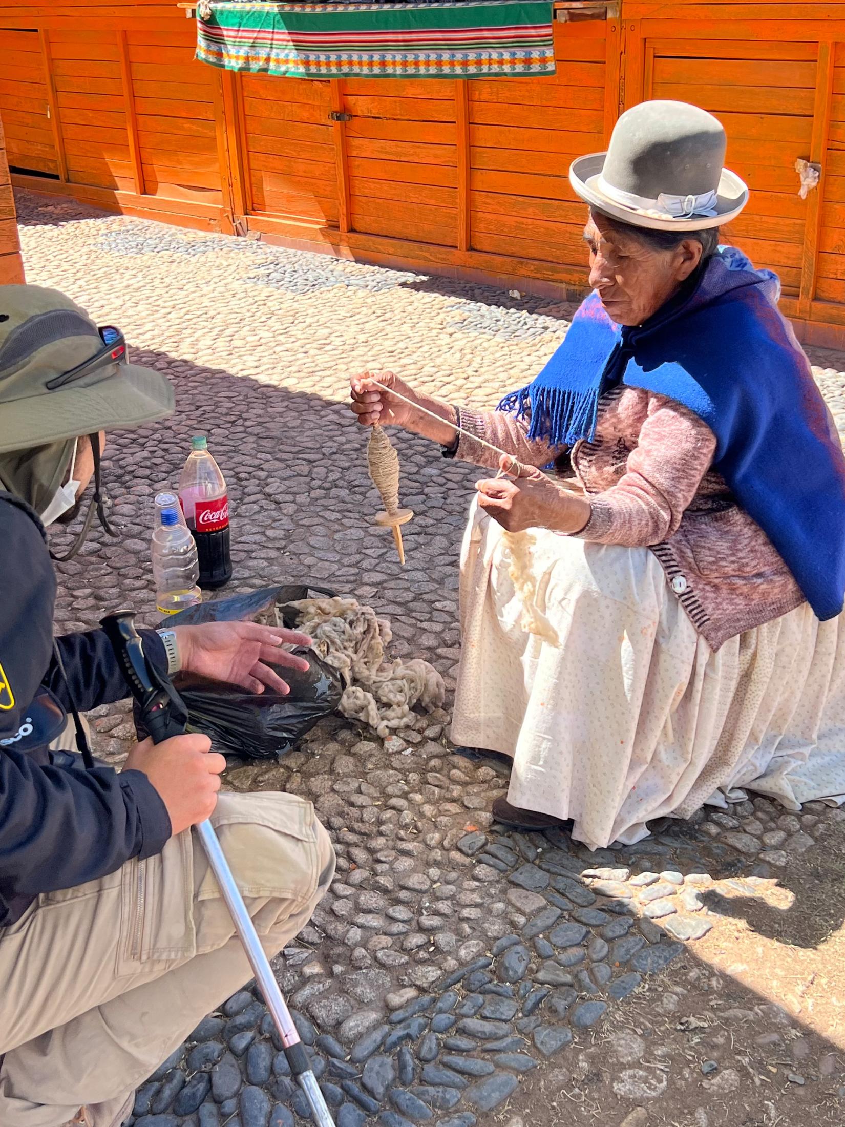 A woman is using traditional technique to make yarn out of raw materials.