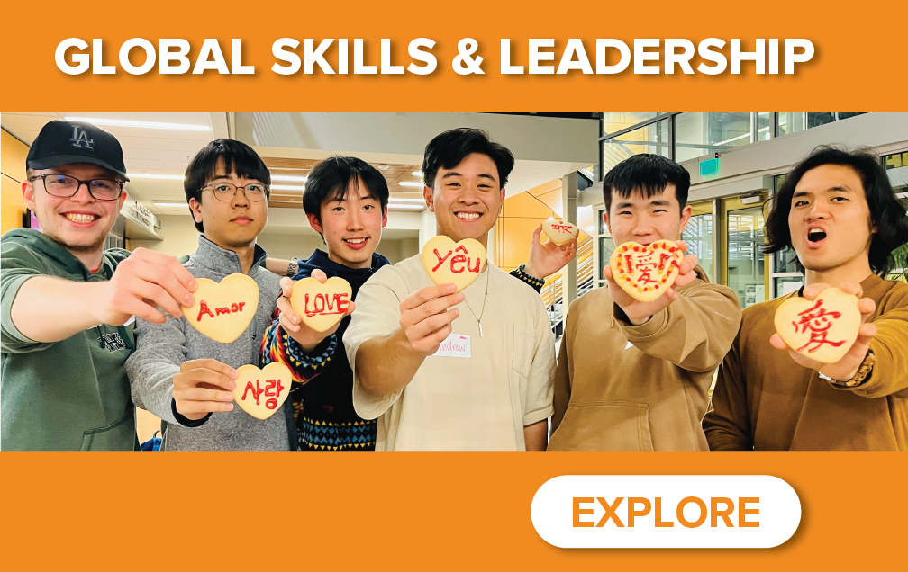 A group of six smiling individuals holds heart-shaped cookies with the word "love" written in various languages. The image is titled "Global Skills & Leadership."