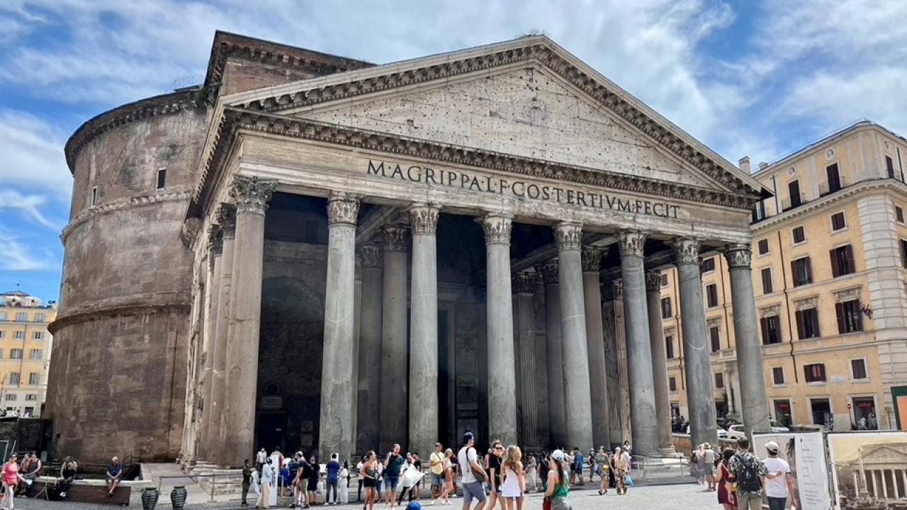 Students walking around in front of an iconic building in Rome, Italy