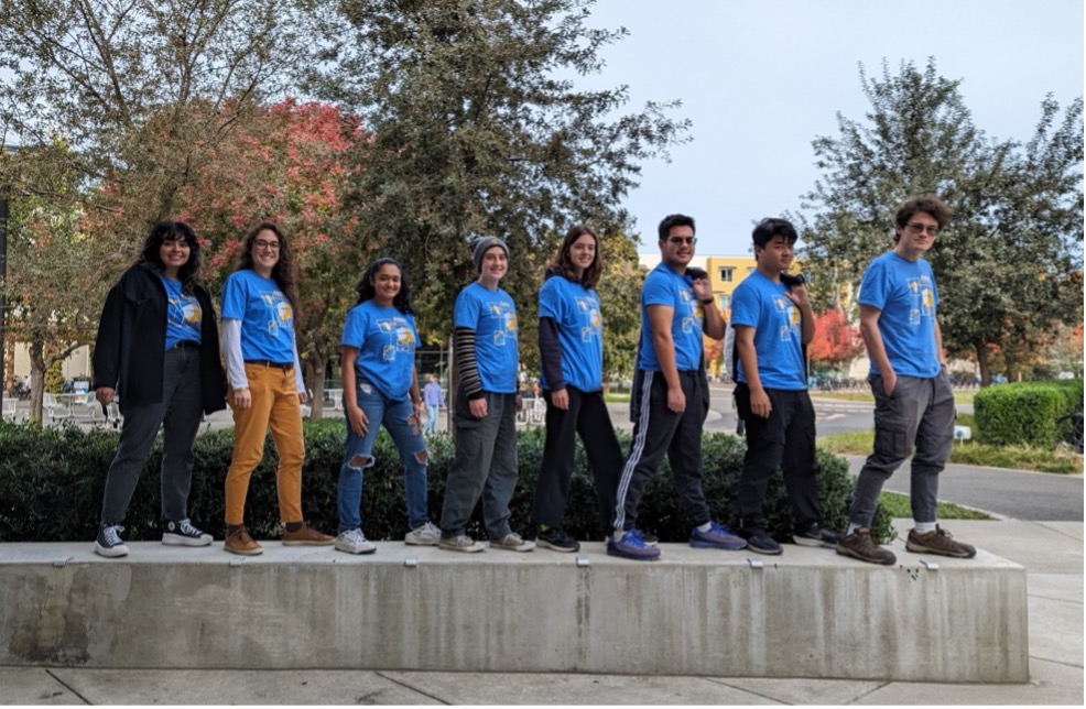Group of students stand in a line and smile for the camera.