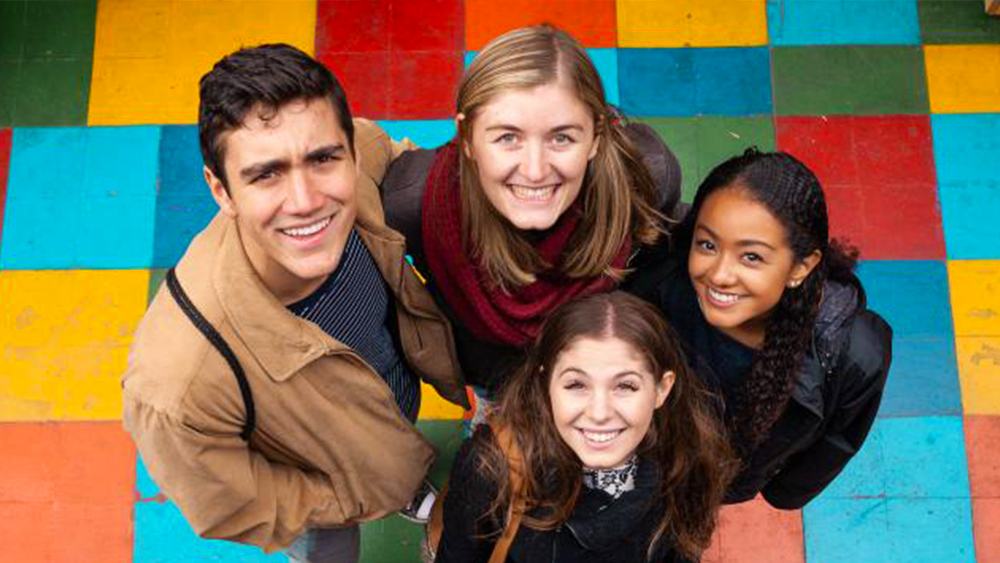Photo of four students looking up at the camera smiling