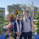 Two smiling people on a rooftop garden with colorful vertical planters and city skyline
