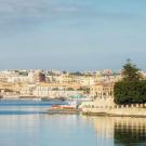 Mediterranean coastal town, photograph with beige buildings along calm blue harbor
