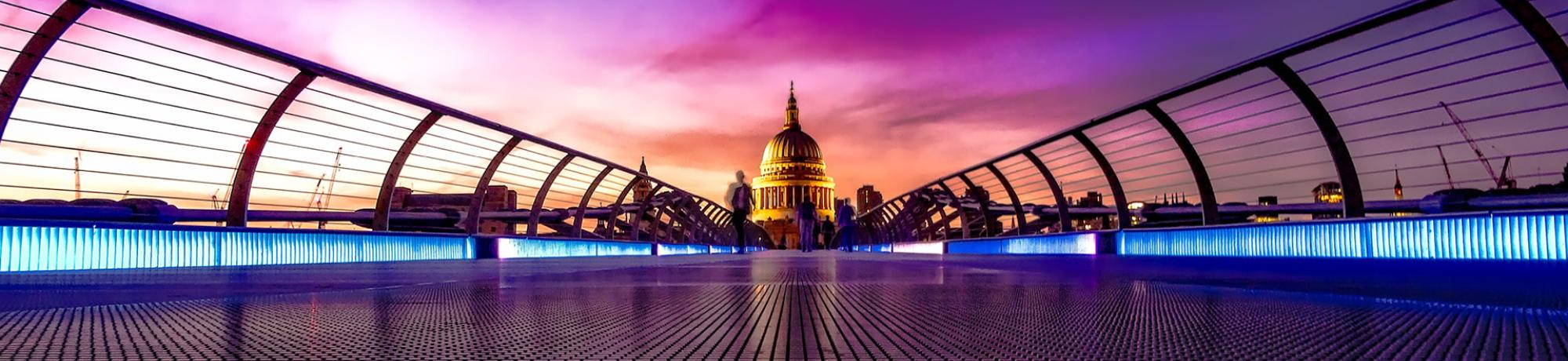 View of Millennium Bridge with St. Paul's Cathedral in the background during sunset.